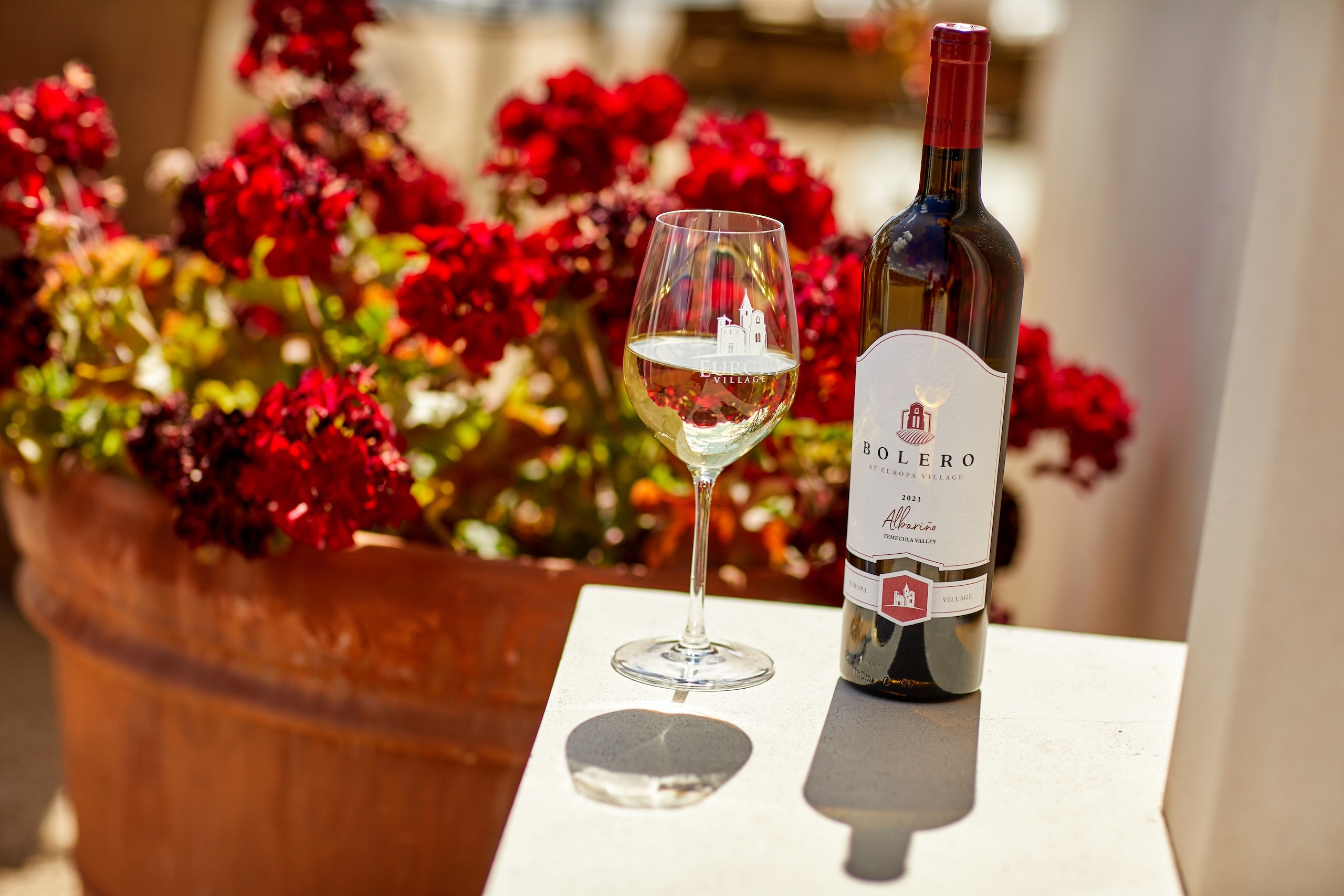 a wine bottle and a glass with red flowers