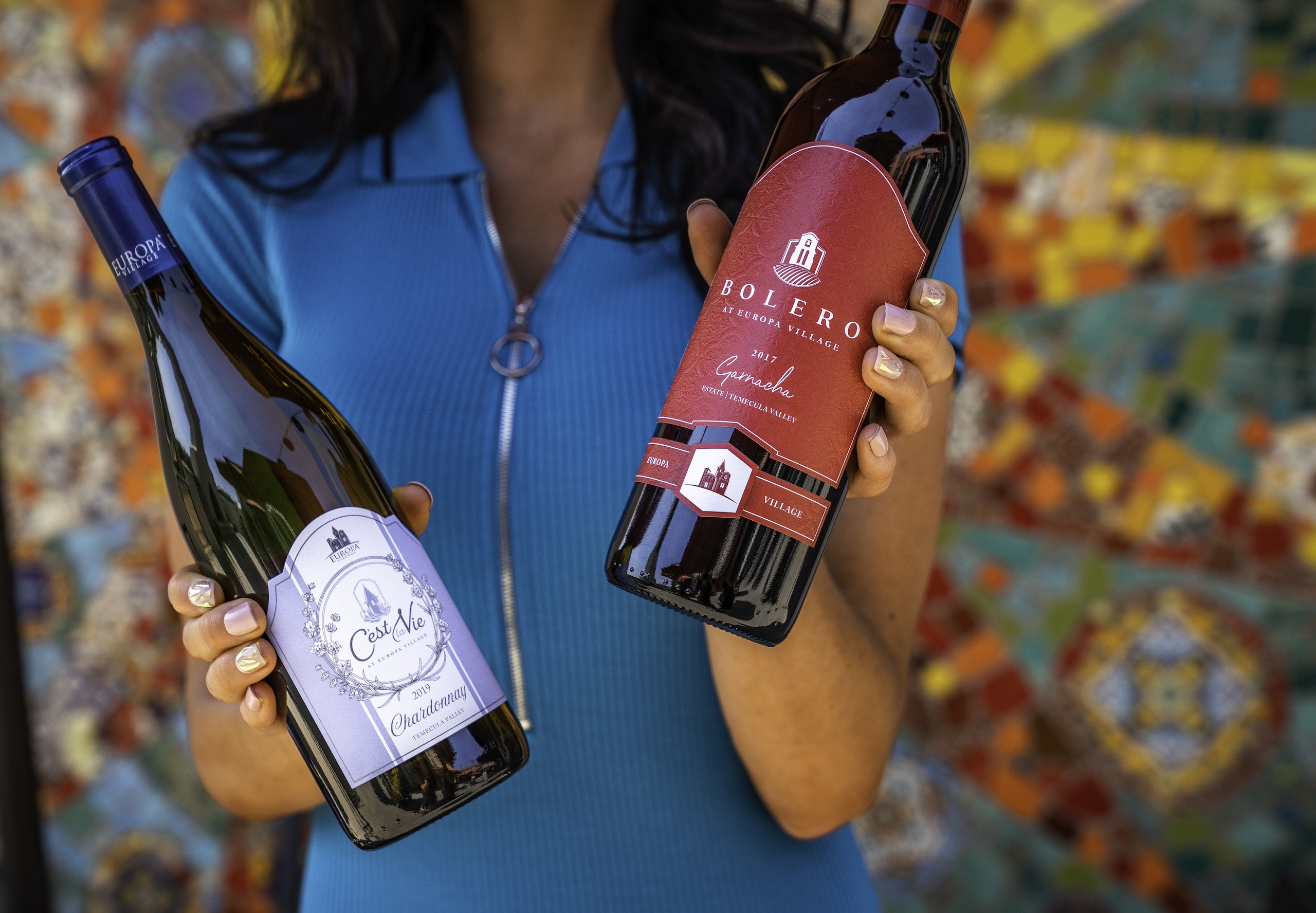 a woman holding two bottles of wine