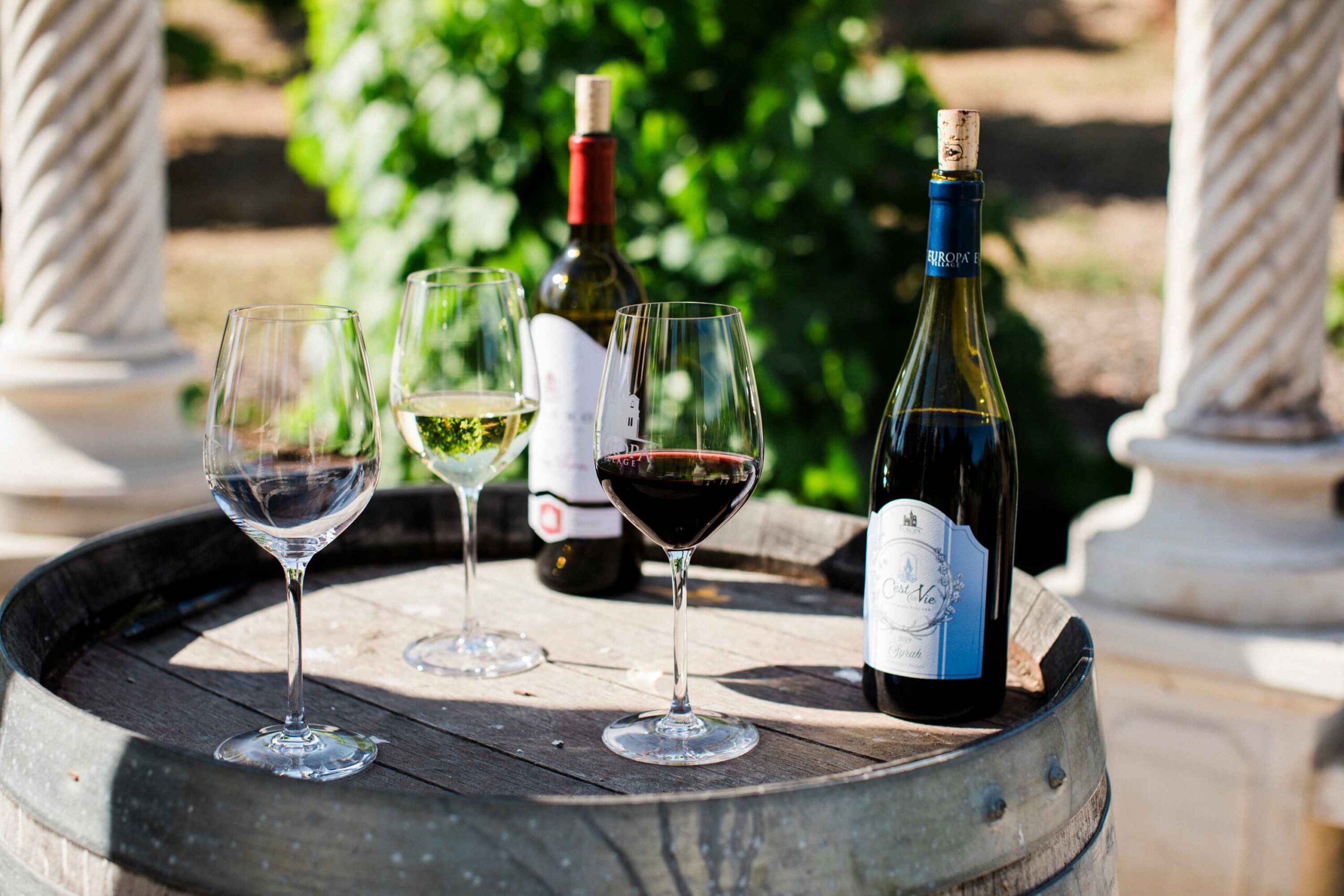 bottles and glasses sitting on a wooden barrel